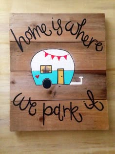 a wooden sign with the words home is where we park it on it and a camper trailer painted on it