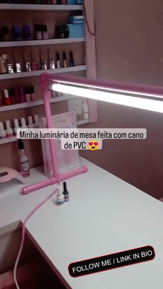 a pink light sitting on top of a white desk next to a shelf filled with bottles