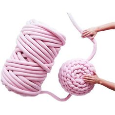 a pink ball of yarn being held by two hands