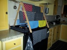 a kitchen with yellow cabinets and black stove top burner, towel rack on the wall