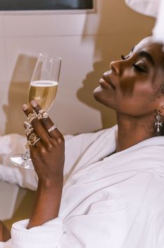 a woman laying in bed holding a glass of wine