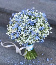 a bouquet of blue and white flowers on the ground with a ribbon tied around it