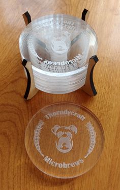 three clear cups sitting next to each other on top of a wooden table with an engraved logo