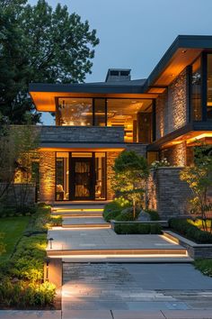 a modern house lit up at night with steps leading to the front door and patio