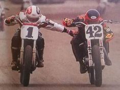 two motorcyclists are touching hands on their bikes in front of the camera