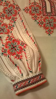 two pieces of white and red crocheted clothing on top of a tablecloth