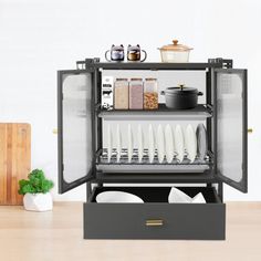 an open cabinet with dishes and utensils in it on top of a wooden table