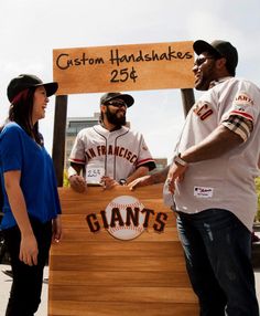 a group of people standing around a giant wooden sign with giants on it's side