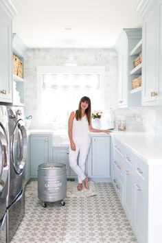 a woman standing in a kitchen next to a washer and dryer