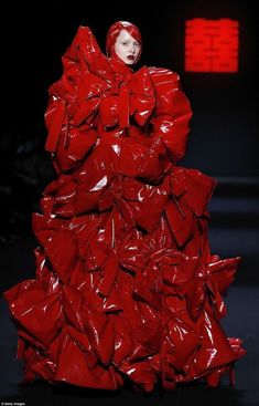 a woman in a red dress on the catwalk wearing plastic wrap around her body