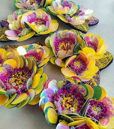 many colorful flowers are arranged in rows on a table with beads and sequins