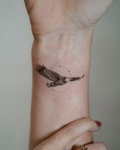 a woman's wrist tattoo with an eagle on it