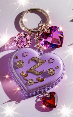 a purple heart shaped keychain sitting on top of a white surface with lots of diamonds