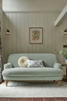 a living room with a blue couch and some flowers on the wall next to it