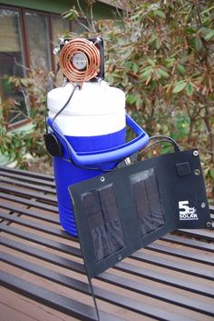 a solar powered air conditioner sitting on top of a wooden table next to a blue and white cooler