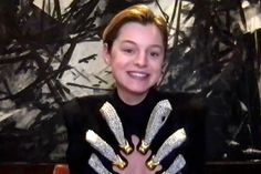 a woman wearing gold and silver gloves smiling at the camera with her hands in front of her chest