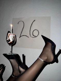 a woman wearing high heels and stockings holding a wine glass with a candle in it