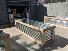 two wooden benches sitting next to each other in front of a garage door with metal slats on the sides