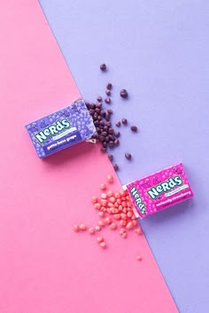 two candy bars are laying next to each other on a pink and purple background with scattered chocolate chips