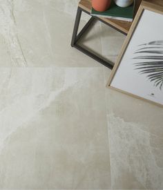 a white marble tile floor with a plant and vases on the side table next to it