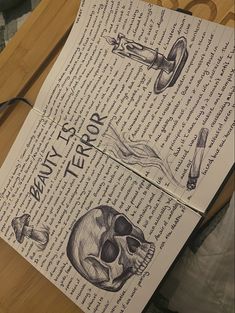 an open book with drawings of skulls and bones on it sitting on a wooden table