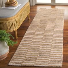 a beige rug on the floor in front of a wooden table and chair with a potted plant next to it