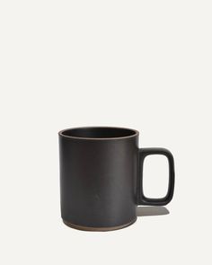 a black coffee mug sitting on top of a white table