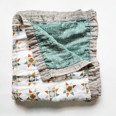 the blanket is folded on top of the bedding with an orange and green pattern