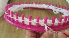 a person is holding a pink and white comb with crochet trimming it