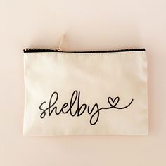 a white zipper bag with the word shelby written in black ink on it