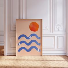 an orange sitting on top of a wooden floor next to a blue and white painting