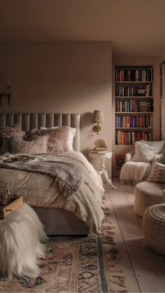 Cozy bedroom with a bed, fluffy blankets, armchair, and a bookshelf filled with books. Apt Decor, Design A Space, Soft Layers, Fluffy Blankets, Soft Textiles