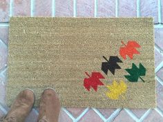 a person standing next to a door mat with leaves on it