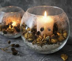 two glass vases filled with flowers and lit candles on top of a stone surface