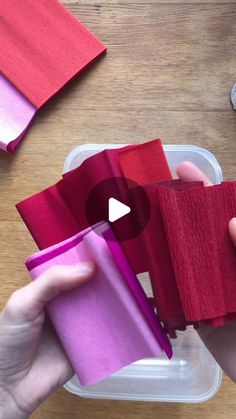 two hands holding red and pink napkins on top of a table