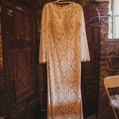 a white lace dress hanging on a wooden door