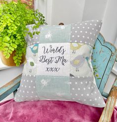 a decorative pillow with words on it sitting on a chair next to a potted plant