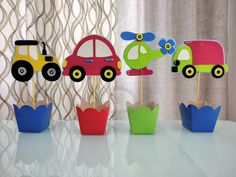 three cupcakes with cars and trucks on them sitting in front of a curtain