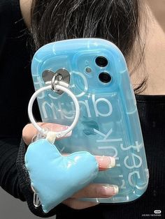 a woman holding a cell phone case with a heart keychain attached to it