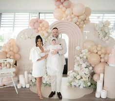 a man, woman and child standing in front of a backdrop with balloons on it