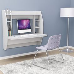 a desk with a computer on it and a chair next to it in front of a blue wall