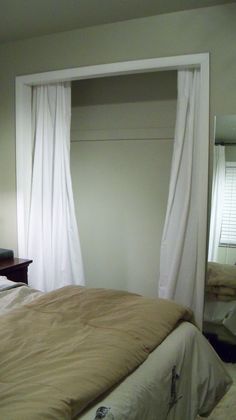 a bed sitting in a bedroom next to a window with white drapes on it