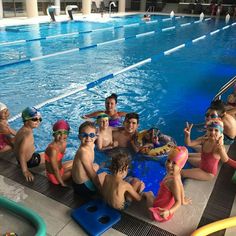 a group of kids in swim suits and goggles sitting on the edge of a swimming pool