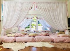 a bedroom with pink bedding and white drapes