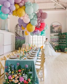 a bride and groom standing in front of a table with many balloons hanging from the ceiling