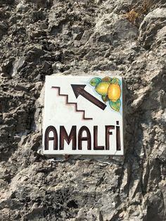 a sign that says amalfi on the side of a stone wall with lemons