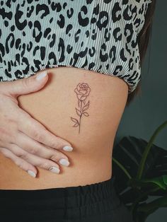 a woman's stomach with a small rose tattoo on her lower belly and side