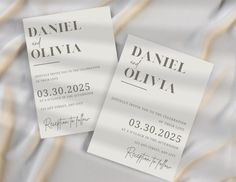 two white wedding cards laying on top of each other