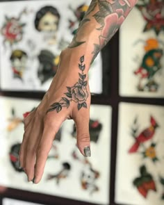 a woman's hand with tattoos on it in front of many framed pictures and flowers