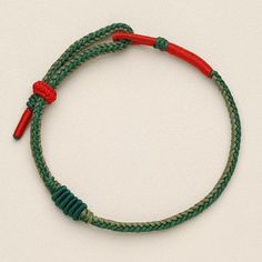 a green and red rope bracelet on a white surface